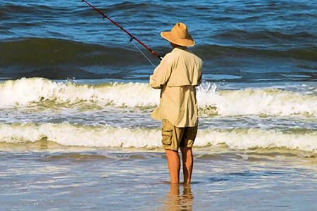 Young man waiting on the beach for a bite.